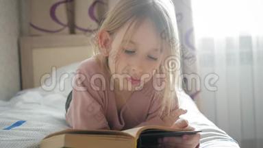 女孩躺在床上看书。 女孩孩子长发可爱睡衣<strong>放松</strong>和阅读童话书。 <strong>惬意</strong>的时光